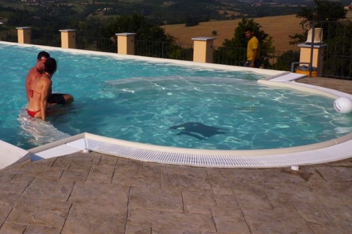 Area relax e giochi d’acqua in piscina interrata con sfioro e cascata a stramazzo